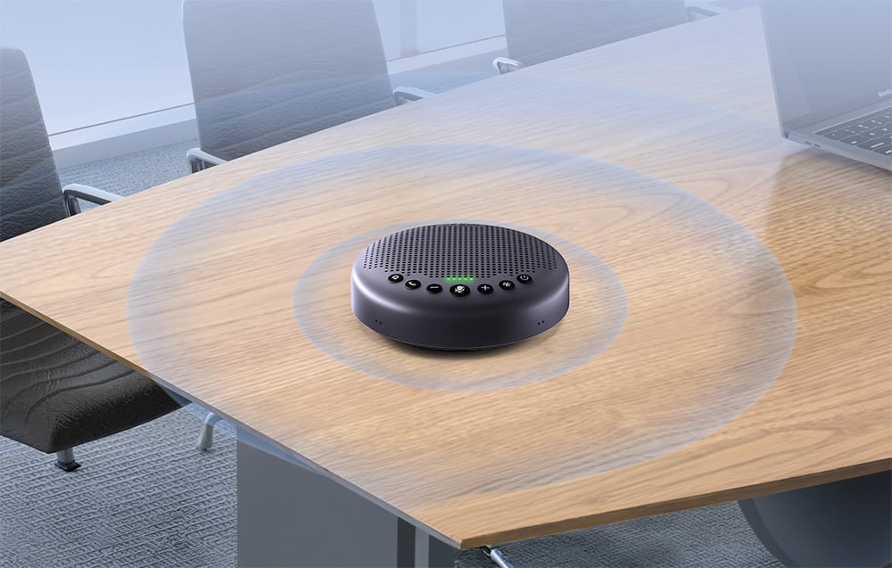 Ένα στρογγυλό ηχείο συνεδριάσεων βρίσκεται στο κέντρο ενός ξύλινου τραπεζιού σε ένα γραφείο, με γραφικούς κύκλους να ακτινοβολούν γύρω του για να συμβολίσουν την εμβέλεια λήψης ήχου