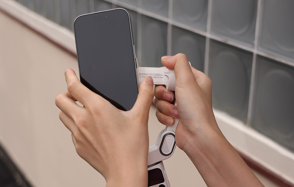 Χέρια που συνδέουν ένα smartphone σε μια μαγνητική βάση πάνω σε ένα gimbal.