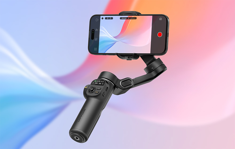 Ένα gimbal για smartphone με ένα τηλέφωνο σε λειτουργία εγγραφής μπροστά από ένα πολύχρωμο φόντο με ντεγκραντέ.