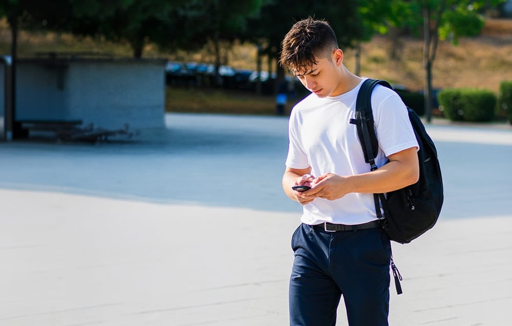 Ένας νεαρός άνδρας με σακίδιο και smartphone στο χέρι