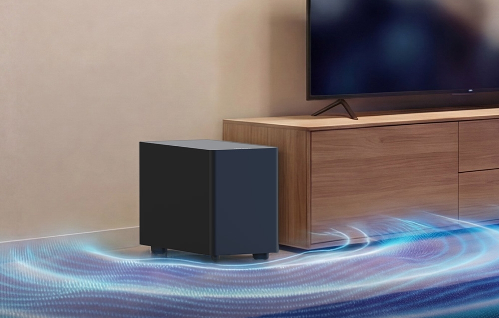 Ένα ασύρματο subwoofer στο πάτωμα δίπλα σε ένα έπιπλο τηλεόρασης