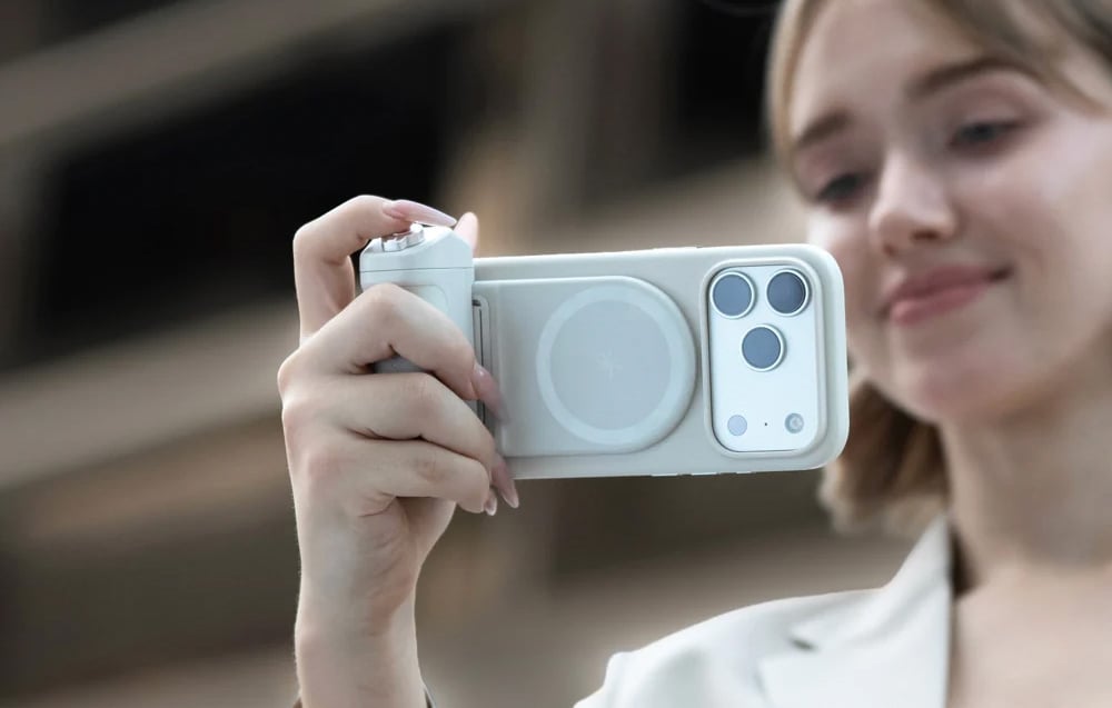 Μια γυναίκα που κρατά ένα smartphone με τη βάση στήριξης προσαρτημένη και τραβάει φωτογραφία σε εξωτερικό χώρο