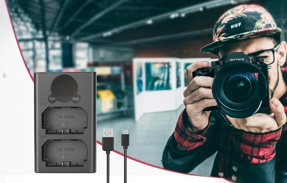 Ένας φορτιστής δύο μπαταριών με καλώδιο USB δίπλα σε έναν φωτογράφο που τραβάει φωτογραφία με μια φωτογραφική μηχανή.