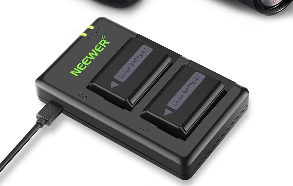 Ένας μαύρος φορτιστής USB Neewer με δύο θύρες, με δύο μπαταρίες ιόντων λιθίου τοποθετημένες.