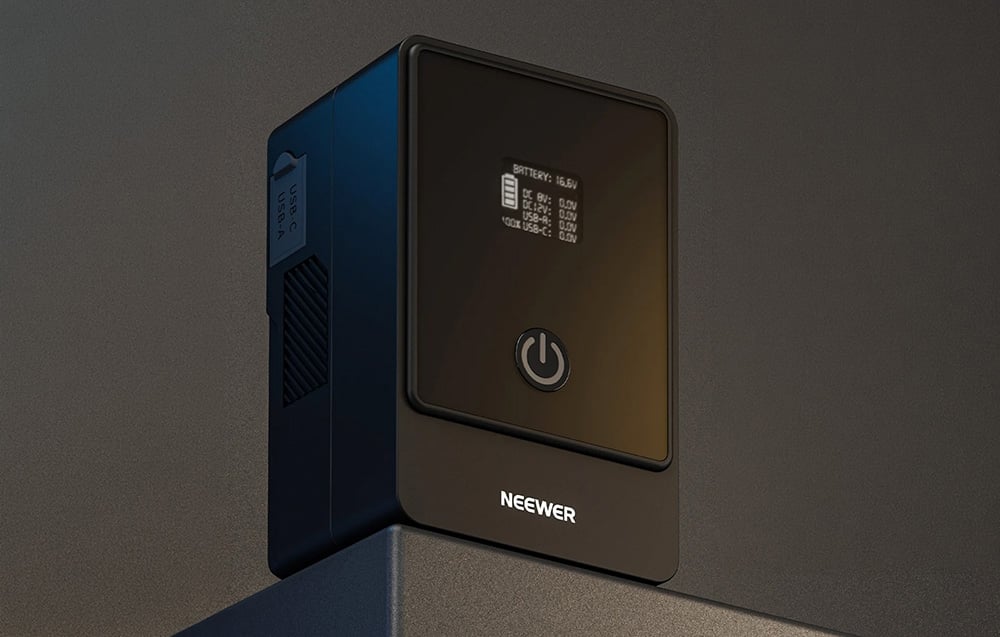 Μαύρη μπαταρία Neewer V-Mount με οθόνη LCD και κουμπί τροφοδοσίας με οπίσθιο φωτισμό σε σκούρο φόντο.