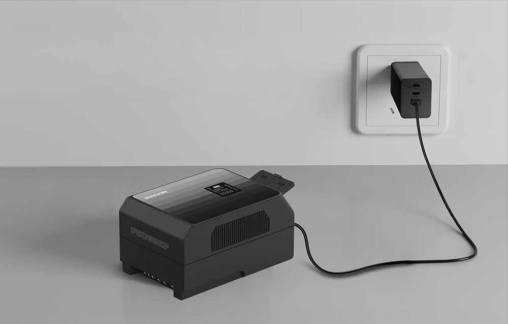 Μπαταρία Neewer συνδεδεμένη μέσω καλωδίου USB σε μαύρο φορτιστή AC που είναι συνδεδεμένος σε λευκή πρίζα τοίχου.