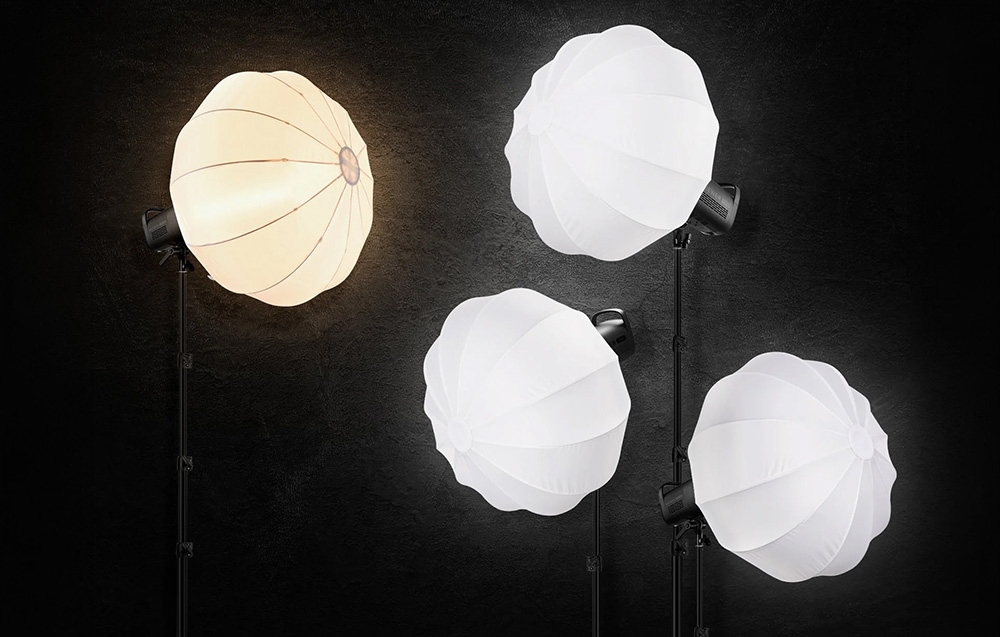 Τέσσερα φώτα στούντιο με softbox φανάρι σε μαύρο φόντο, ένα από τα οποία εκπέμπει ζεστό, κίτρινο φως.