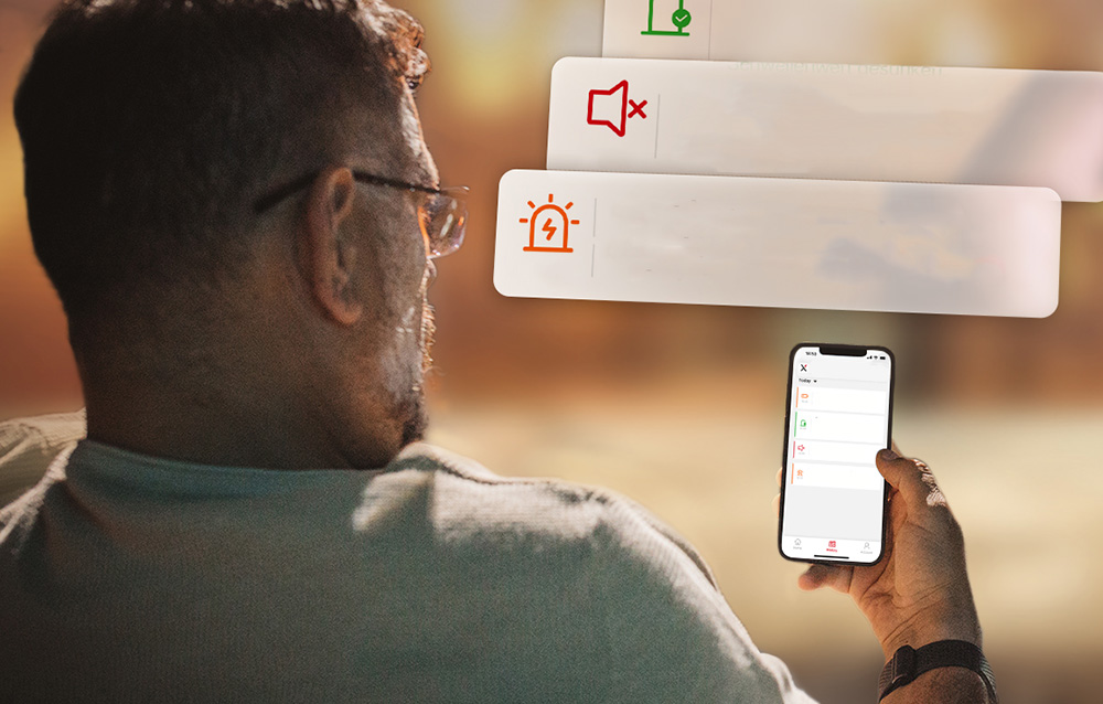 Ένας άνδρας κοιτάζει την οθόνη του smartphone του, η οποία εμφανίζει μια λίστα ειδοποιήσεων σχετικά με τον συναγερμό και τη σίγαση του ήχου