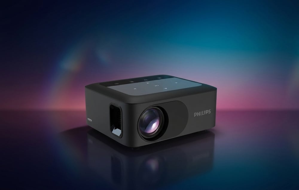 Μαύρος προβολέας PHILIPS με την ένδειξη «HDMI» στο πλάι, τοποθετημένος σε σκούρο φόντο με πολύχρωμες αντανακλάσεις φωτός