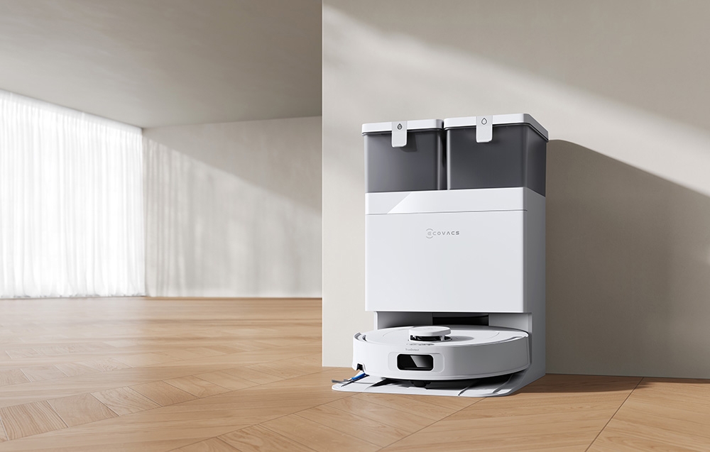 Ρομπότ καθαρισμού ECOVACS στη βάση φόρτισης πάνω σε ανοιχτόχρωμο δάπεδο σε φωτεινό δωμάτιο