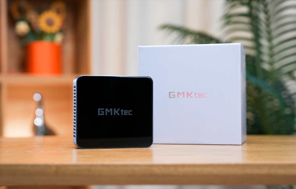 Ο μίνι υπολογιστής GMKtec M3 Pro τοποθετημένος δίπλα στην αρχική του συσκευασία πάνω σε ξύλινη επιφάνεια.