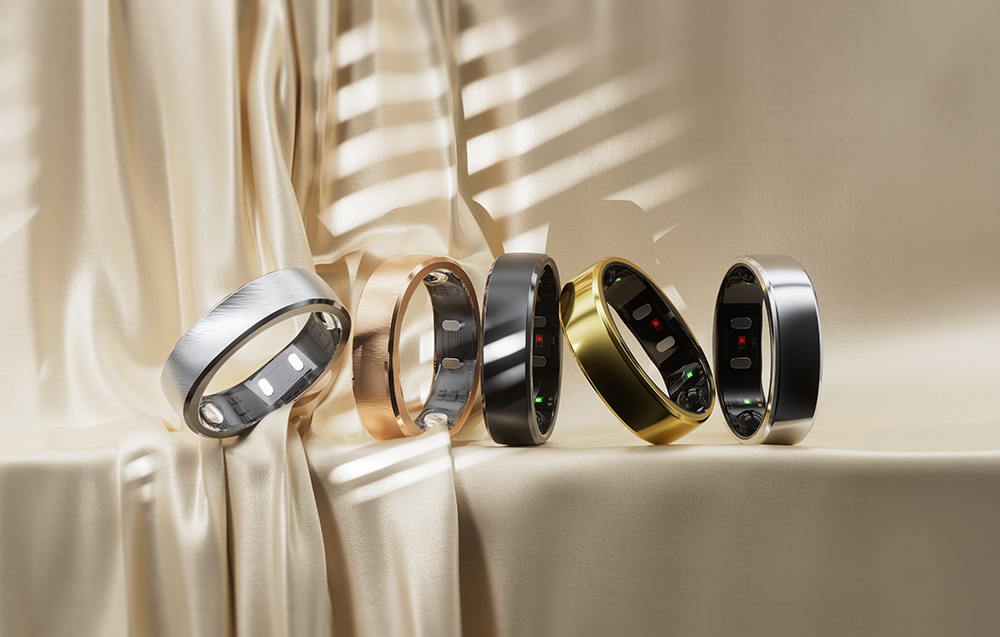 Πέντε έξυπνα δαχτυλίδια διατεταγμένα σε σειρά πάνω σε ένα μπεζ, σατινέ ύφασμα με σκιές