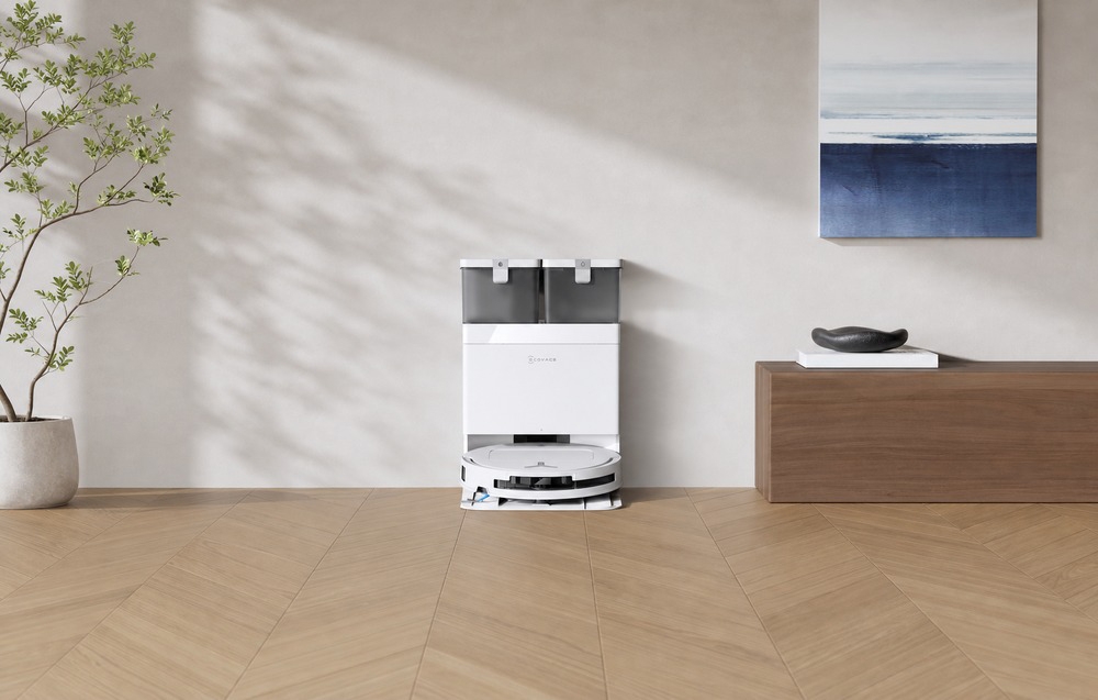 Το ρομπότ ECOVACS στη βάση φόρτισης, με μια ξύλινη συρταριέρα και έναν πίνακα στα δεξιά