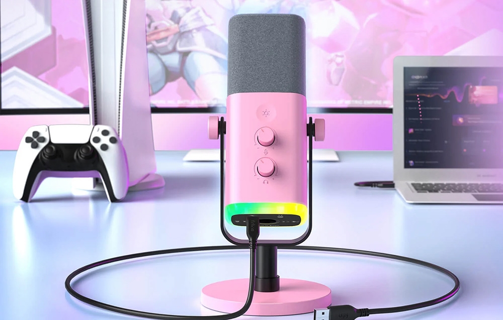 Ένα ροζ μικρόφωνο Fifine με οπίσθιο φωτισμό RGB σε ένα gaming setup με κονσόλα και φορητό υπολογιστή Δύο άτομα καθισμένα σε ένα ξύλινο τραπέζι με μικρόφωνα Fifine σε βάσεις, κούπες και ένα πιάτο με φρούτα