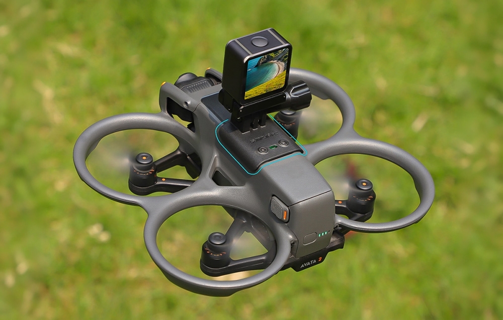 Κάτοψη του drone που πετά πάνω από γρασίδι, με γενικό προσαρμογέα και μικρή κάμερα δράσης στο σώμα.