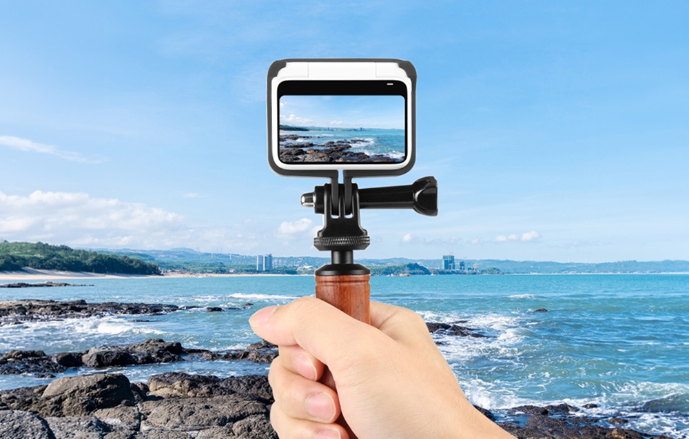 Κάμερα Insta360 GO 3 σε πλαίσιο στήριξης προσαρτημένο σε ξύλινη λαβή χειρός δίπλα στη θάλασσα