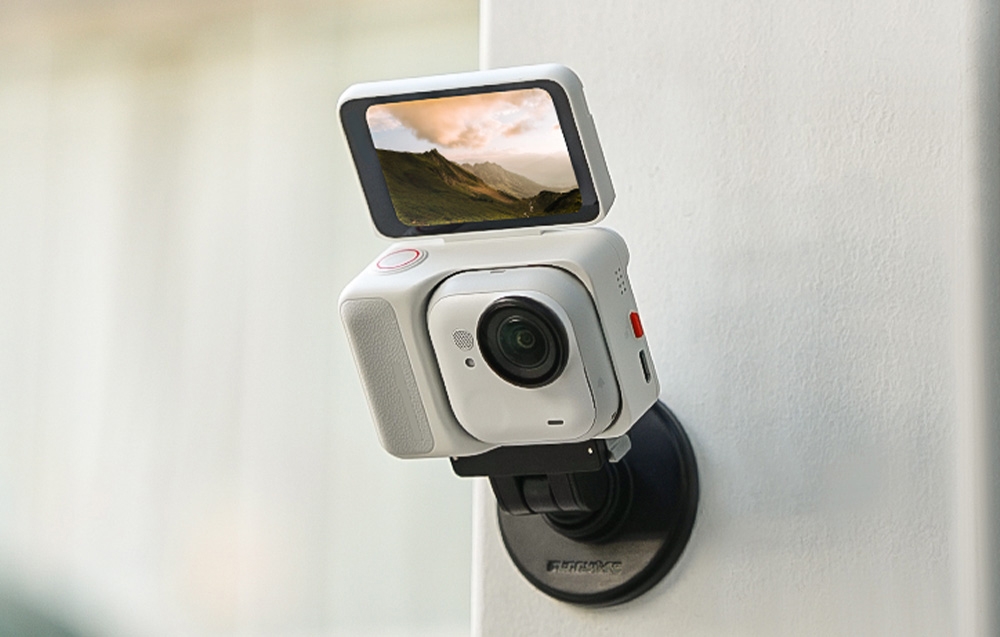 Λευκή κάμερα Insta360 GO 3 με ανυψωμένη οθόνη, τοποθετημένη μαγνητικά σε λευκό στύλο.