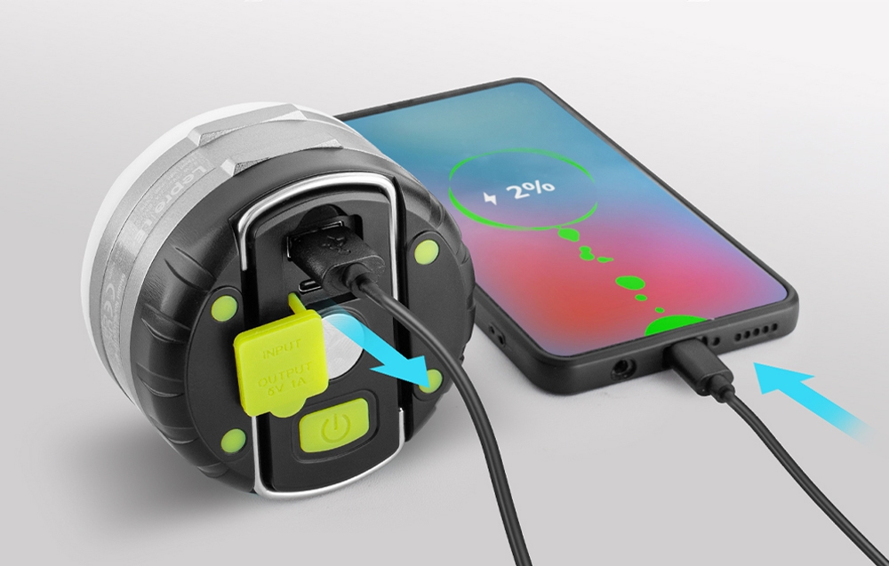 Μια λάμπα κάμπινγκ που λειτουργεί ως power bank, φορτίζοντας ένα μαύρο smartphone που βρίσκεται δίπλα της μέσω καλωδίου.