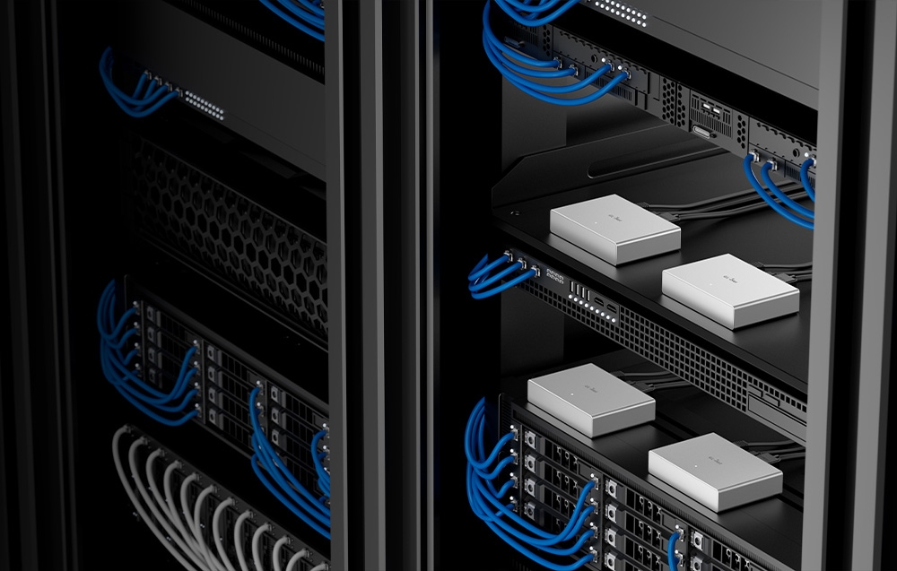 Αρκετοί ασημένιοι διακόπτες KVM τοποθετημένοι σε μαύρα ράφια διακομιστών με μπλε καλώδια