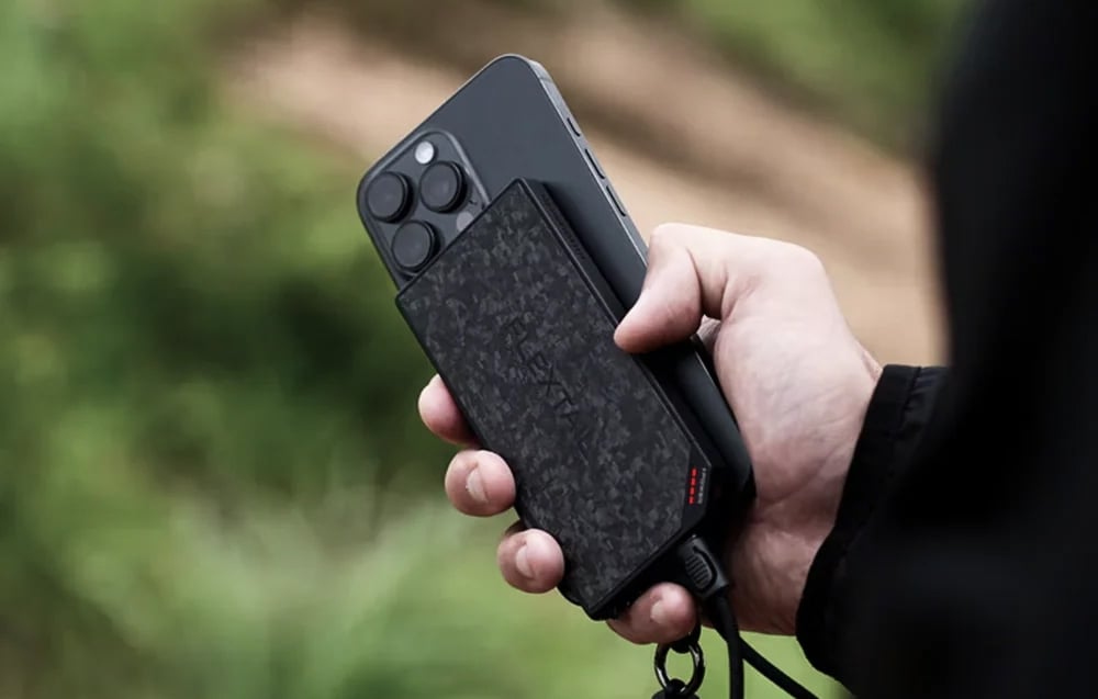 Ένα χέρι κρατά ένα smartphone συνδεδεμένο με καλώδιο στην εξωτερική μπαταρία FLEXTAIL.