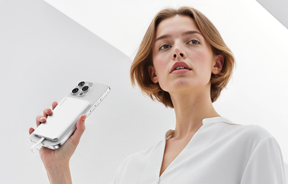 Μια γυναίκα κρατά ένα smartphone με μια μαγνητική εξωτερική μπαταρία FlexTail προσαρτημένη στο πίσω μέρος της συσκευής.
