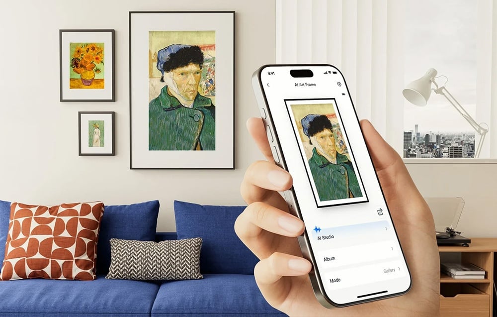 Ένα χέρι που κρατά ένα smartphone στο οποίο εμφανίζεται μια προεπισκόπηση του πορτρέτου του άνδρα, το οποίο κρέμεται επίσης στον τοίχο πίσω από τον καναπέ.