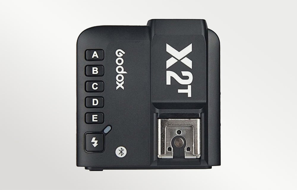 Η κορυφή του τηλεχειριστήριου φλας Godox X2T, όπου φαίνονται τα κουμπιά ομάδων, το λογότυπο της μάρκας και η υποδοχή στήριξης.