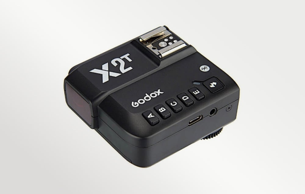 Το μαύρο τηλεχειριστήριο φλας Godox X2T σε πλάγια όψη, με ορατή τη θύρα και τα κουμπιά.