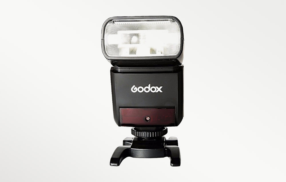 Το μαύρο φλας Godox TT350 σε όψη από μπροστά, τοποθετημένο στη βάση «cold shoe» που περιλαμβάνεται