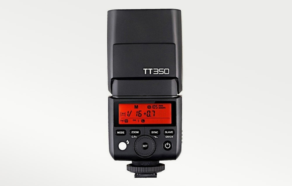 Φλας Godox TT350 από πίσω, με τον πορτοκαλί οπίσθιο φωτισμό της οθόνης LCD ενεργοποιημένο και τον πίνακα ελέγχου ορατό
