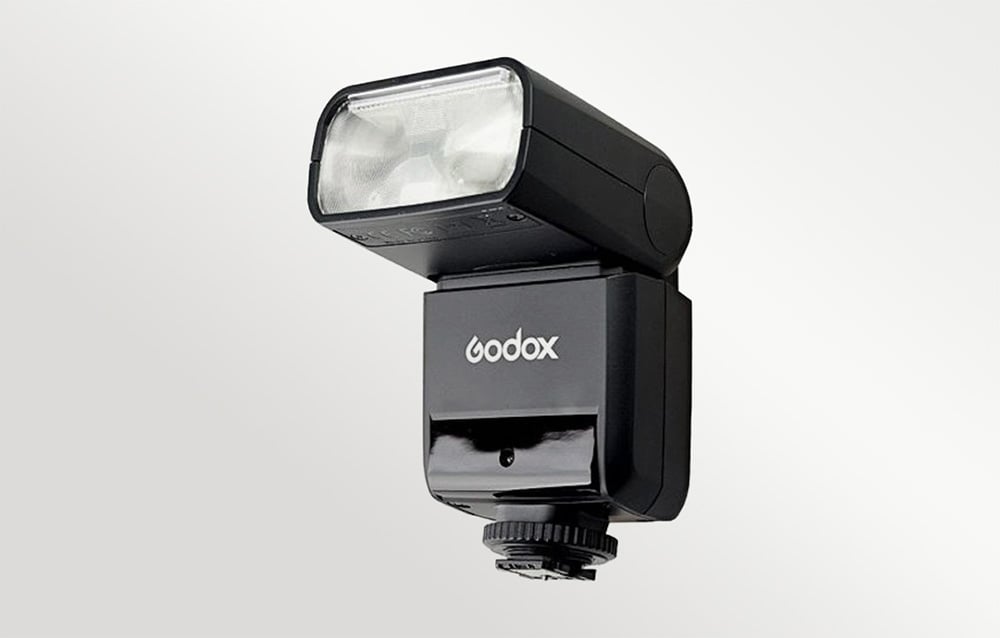 Μαύρο φλας Godox TT350 με την κεφαλή ανυψωμένη, μπροστινή όψη σε γκρι φόντο