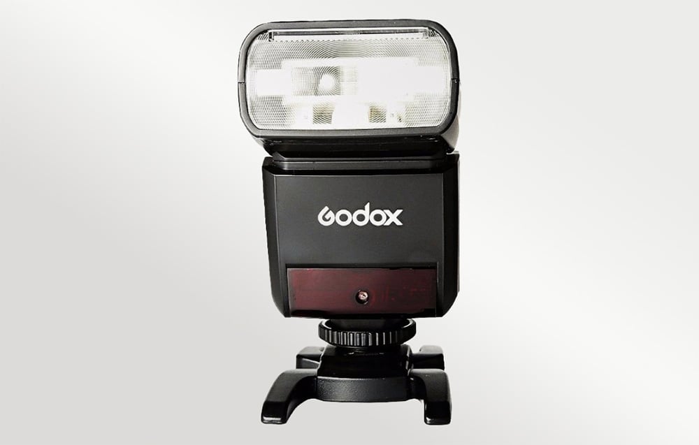 Φλας Godox TT350 τοποθετημένο σε μαύρη υποδοχή hot shoe, μπροστινή όψη με ορατό το λογότυπο του κατασκευαστή