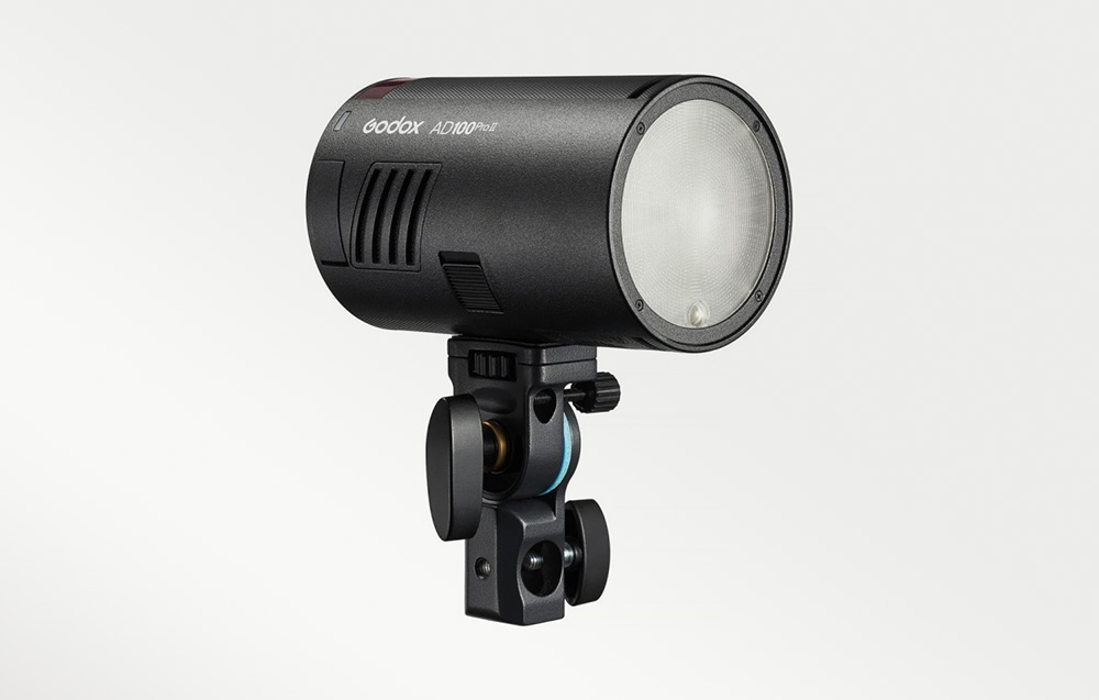 Ένα μαύρο φλας Godox AD100Pro II τοποθετημένο σε βάση τρίποδα με στρογγυλή κεφαλή φλας