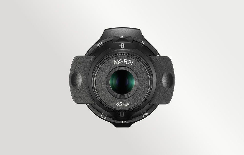 Κοντινή λήψη του εξαρτήματος προβολής Godox AK-R21 με φακό 65 mm από μπροστά σε ανοιχτό γκρι φόντο