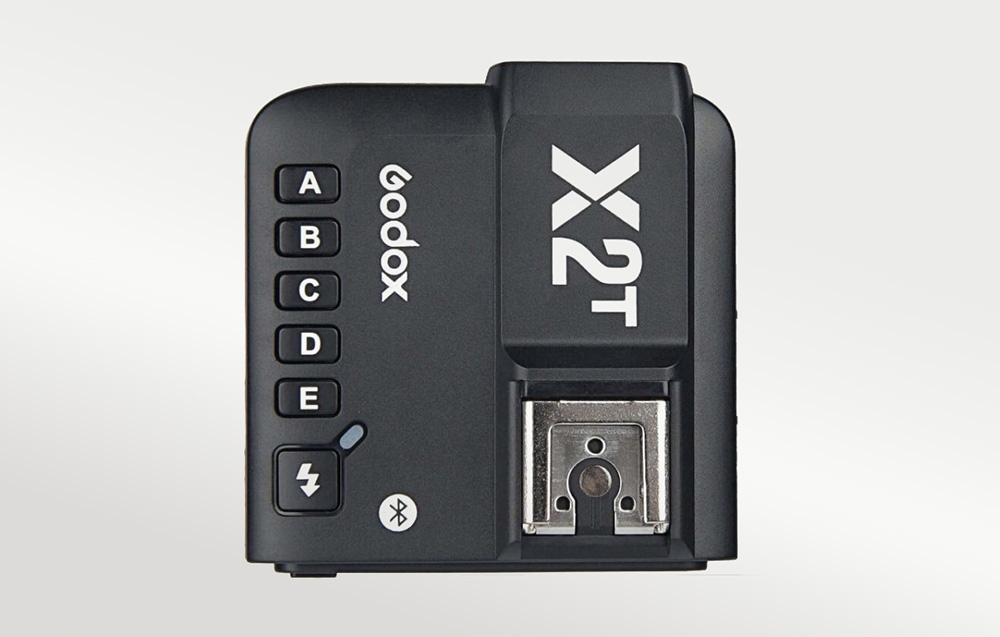 Κάτοψη της μαύρης μονάδας Godox X2T με κουμπιά A–E και μεταλλική βάση σε ανοιχτόχρωμο φόντο
