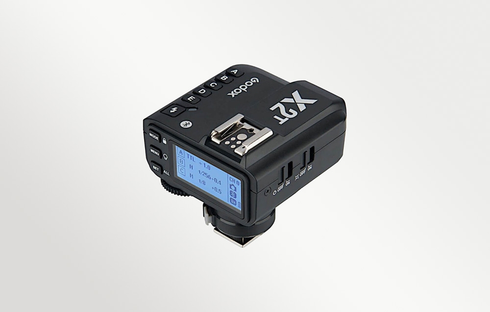 Ο μαύρος ραδιοπομπός Godox X2T, όπως φαίνεται υπό γωνία με την οθόνη LCD με οπίσθιο φωτισμό