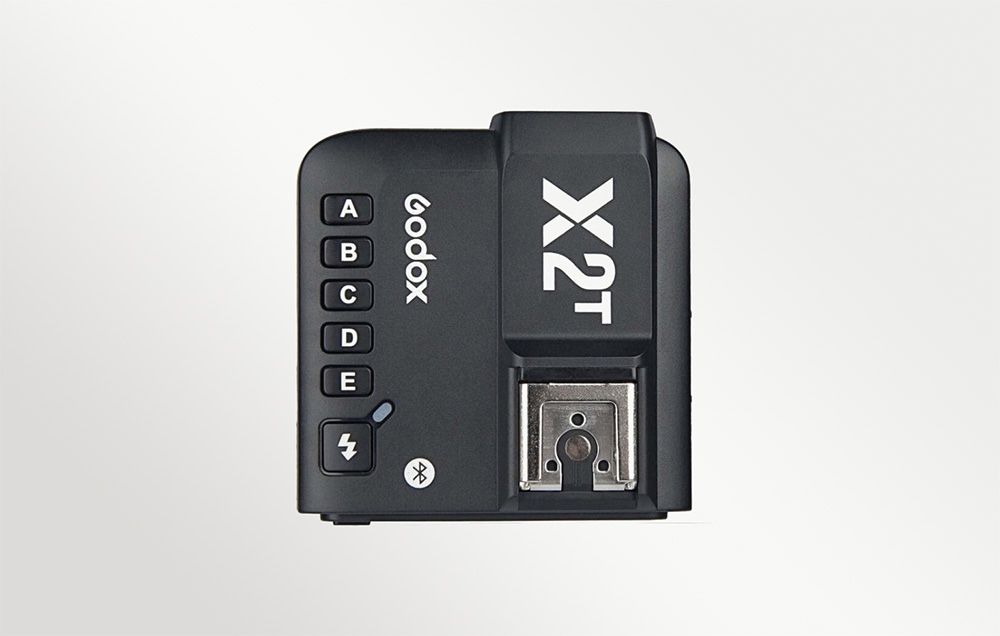 Κάτοψη του μαύρου ραδιοπομπού Godox X2T με ορατά κουμπιά ομάδων και υποδοχή hot shoe