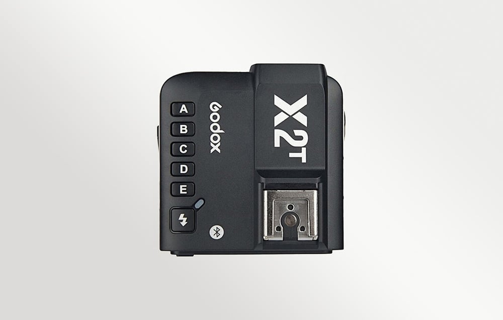 Κάτοψη του μαύρου ραδιοπομπού Godox X2T-N με ορατά κουμπιά ομάδων και υποδοχή hot shoe