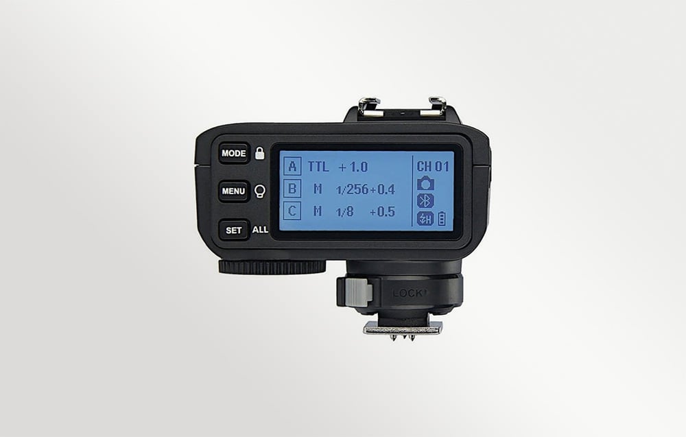 Ο μαύρος ραδιοπομπός Godox X2T-N, όπως φαίνεται από πίσω με την μπλε οθόνη LCD αναμμένη