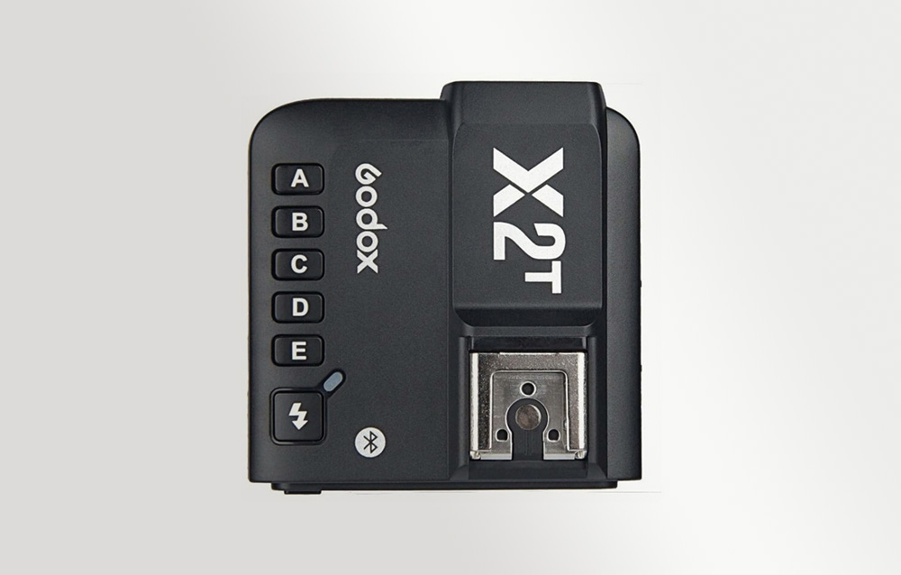 Κάτοψη του μαύρου ραδιοπομπού Godox X2T με ορατά κουμπιά ομάδων και υποδοχή hot shoe