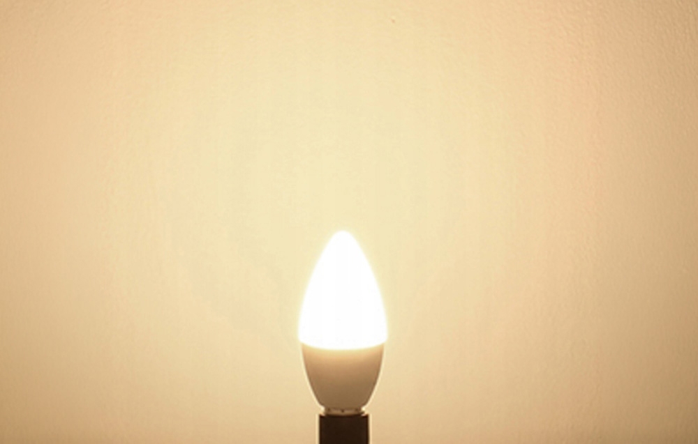Ένας αναμμένος λαμπτήρας LED Lepro E14 με ζεστό χρώμα φωτός σε φωτεινό φόντο, τοποθετημένος σε υποδοχή λαμπτήρα