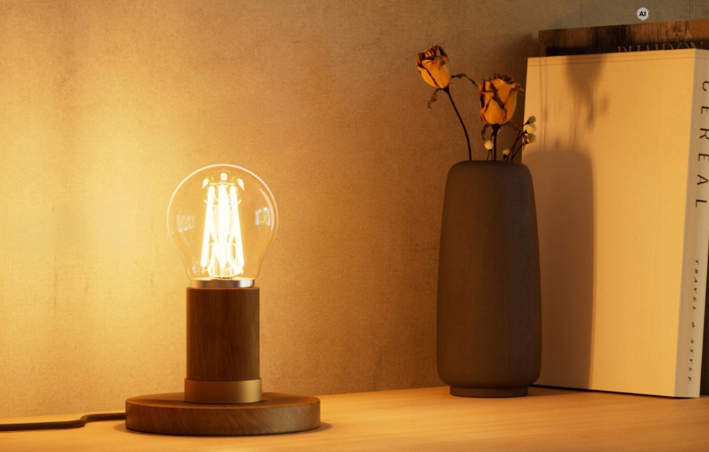 Ένας αναμμένος διακοσμητικός λαμπτήρας LED σε ξύλινη βάση, τοποθετημένος πάνω σε τραπέζι δίπλα σε ένα βάζο με αποξηραμένα τριαντάφυλλα
