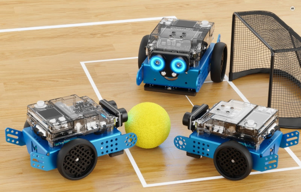 Τρία μπλε εκπαιδευτικά ρομπότ Makeblock mBot2 που παίζουν ποδόσφαιρο σε ένα μικροσκοπικό γήπεδο με τέρμα