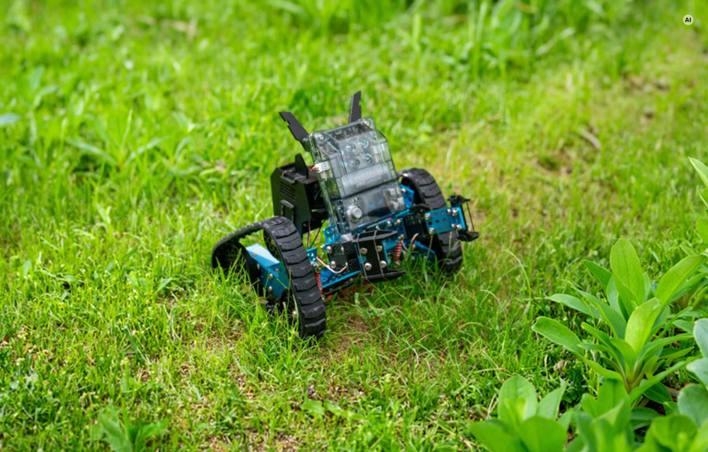 Ένα μπλε και μαύρο εκπαιδευτικό ρομπότ Makeblock mBot Ranger με ερπύστριες στέκεται σε ένα πράσινο γκαζόν στον κήπο