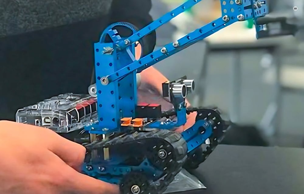 Το μπλε ρομπότ με ερπύστριες Makeblock mBot Ranger κρατημένο στα χέρια κατά τη συναρμολόγηση