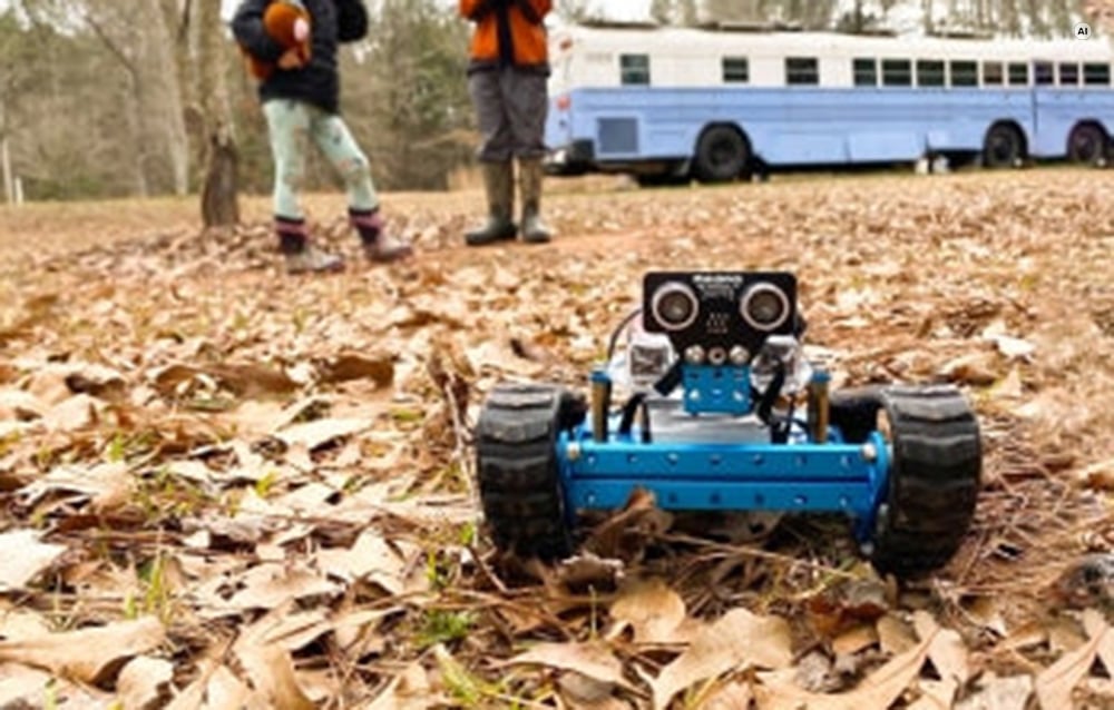 Το μπλε ρομπότ με ερπύστριες Makeblock mBot Ranger κινείται πάνω από πεσμένα φύλλα σε ένα πάρκο