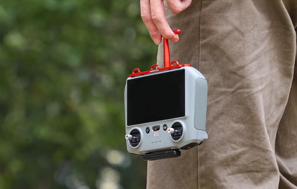 Mężczyzna trzymający controler DJI przy pomocy uchwytu Sunnylife.