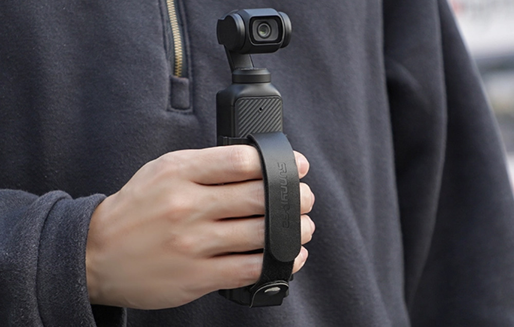 Ανδρας που καταγράφει με την κάμερα DJI OSMO Pocket 3, την οποία κρατάει με τη βάση παλάμης Sunnylife.