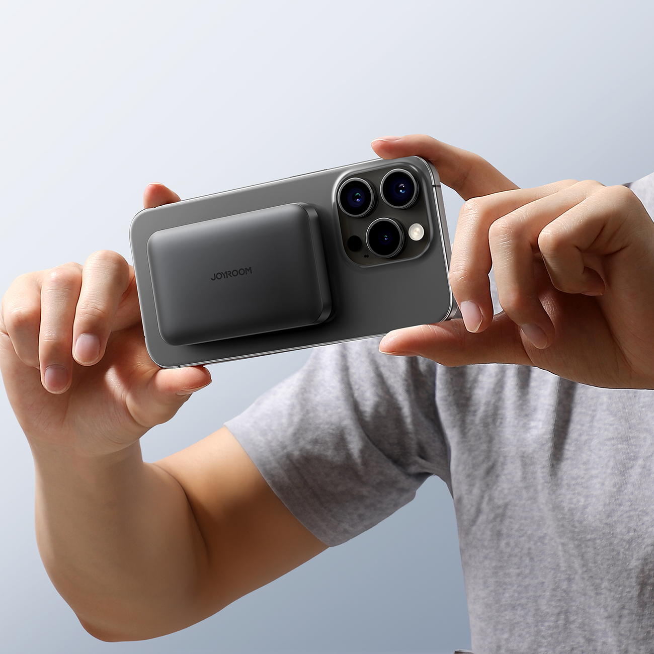 Ένας άντρας που βγάζει φωτογραφία με ένα iPhone με συνδεδεμένη την επαγωγική τράπεζα ισχύος Joyroom JR-W020 Mini